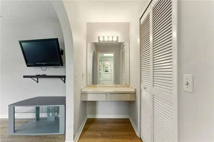 Vanity, across from the bathroom with lvp flooring  and arched walkways.