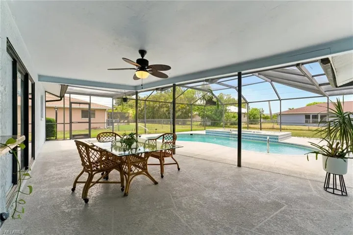 Swimming pool featuring a patio area, screen enclosure, a ceiling fan, and a lawn