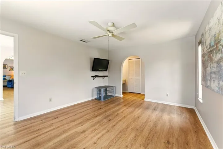 Unfurnished primary bedroom, lvp flooring, celing fan, closets, multiple windows, lots of natural light.
