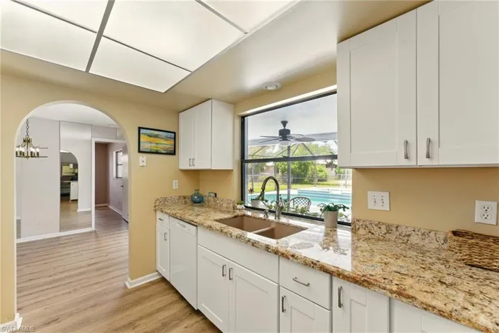 Kitchen featuring arched walkways, light wood-style floors, white cabinets granite counter tops