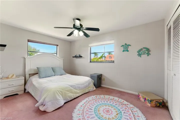 Bedroom featuring a closet, multiple windows, carpet floors, and a ceiling fan
