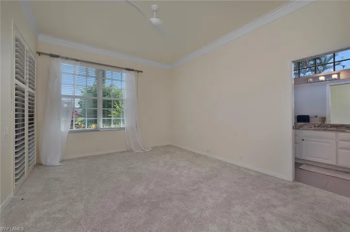 Unfurnished bedroom with light carpet, ornamental molding, sink, ceiling fan, and ensuite bathroom