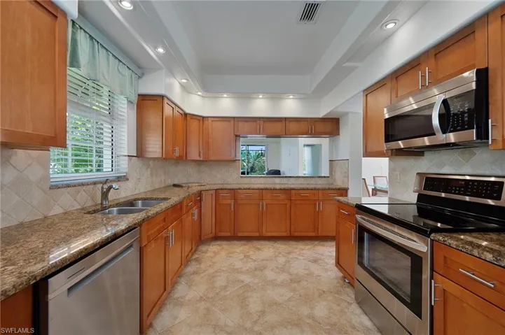 Kitchen featuring a raised ceiling, tasteful backsplash, stainless steel appliances, and sink