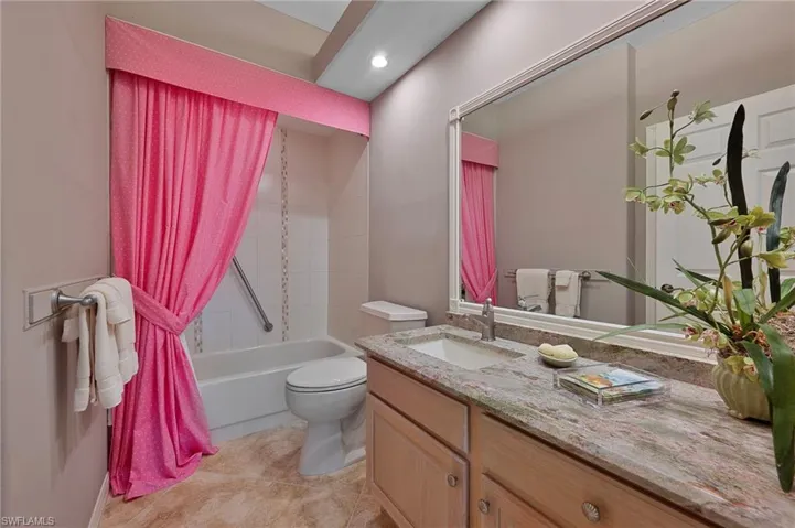 Full bathroom featuring tile patterned flooring, shower / bath combo with shower curtain, toilet, and vanity