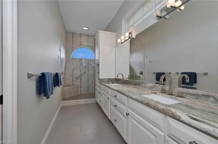 Bathroom with vanity, tiled shower, and tile patterned flooring
