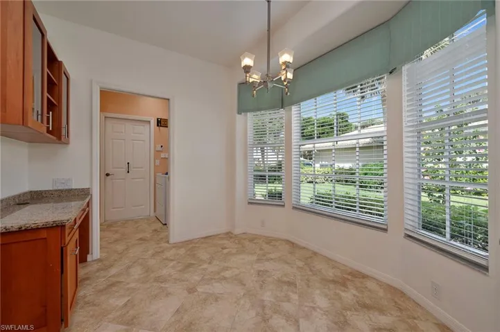 Kitchen featuring plenty of natural light, light stone counters, an inviting chandelier, and hanging light fixtures