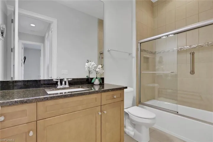 Full bathroom with vanity, shower / bath combination with glass door, and light tile patterned flooring