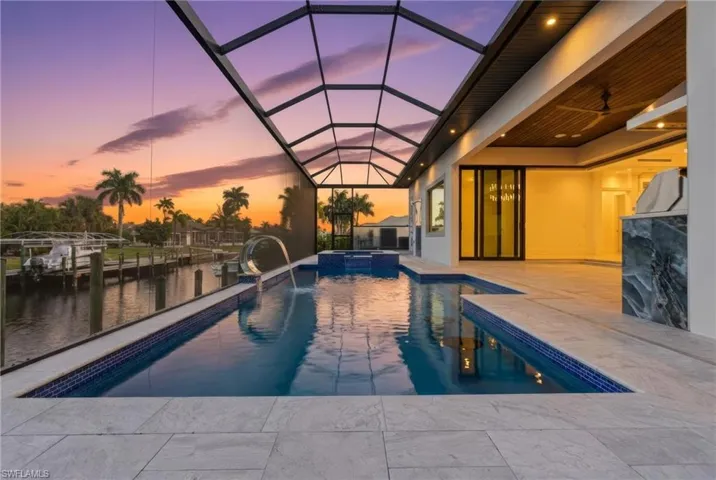 Pool at dusk featuring a saltwater pool and Jacuzzi