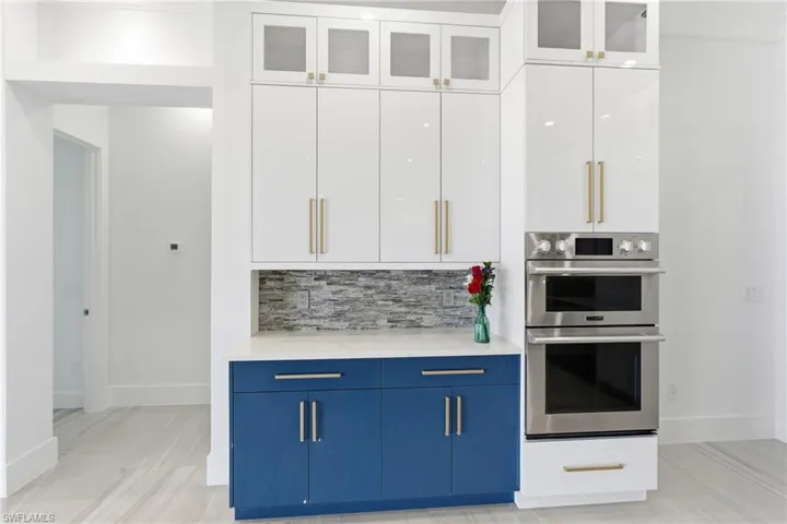 Kitchen featuring white cabinetry, double oven, blue cabinetry, and modern cabinets