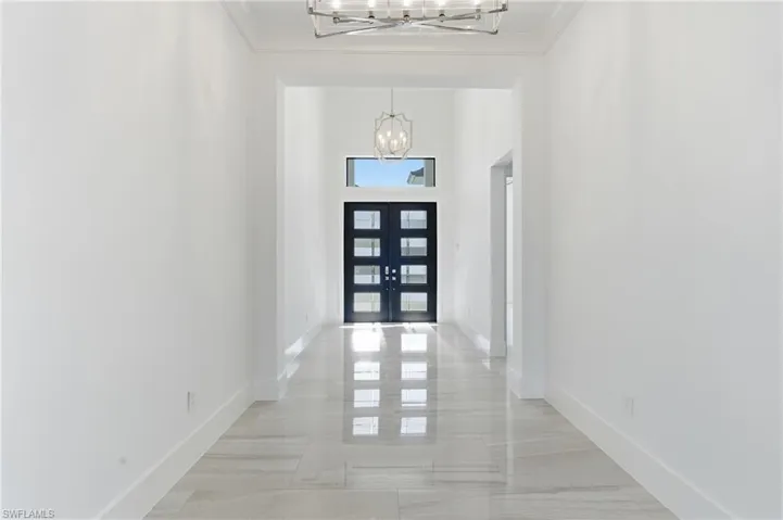 Foyer featuring a high ceiling, french doors, and a chandelier