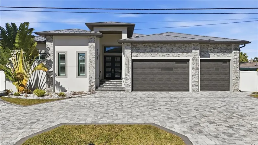View of front of home with a metal roof, a standing seam roof, decorative driveway, an attached garage, and stucco siding