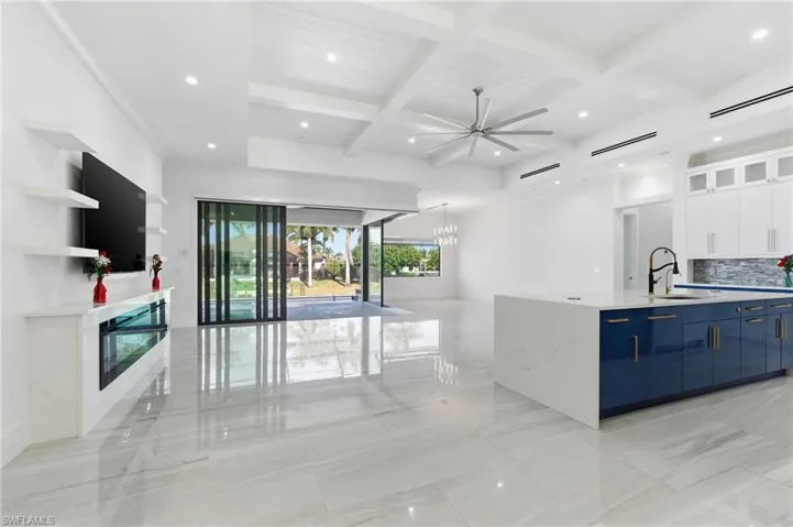 Kitchen with glass insert cabinets, white cabinetry, coffered ceiling, open floor plan, and a ceiling fan