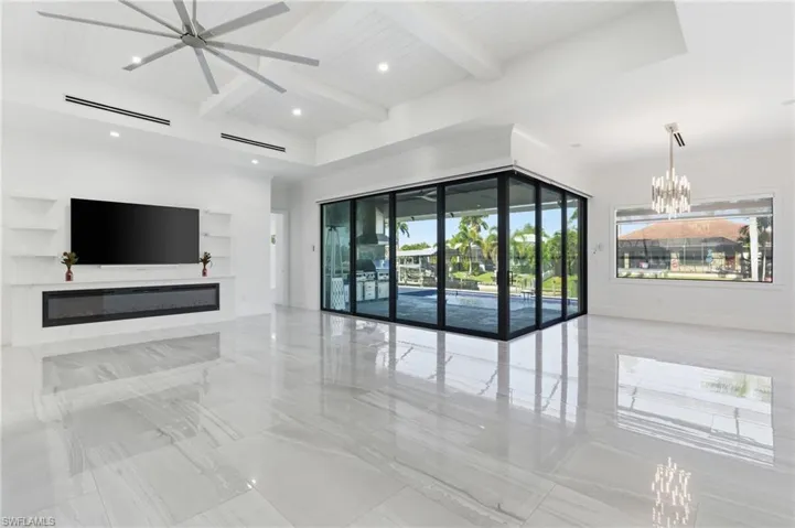 Unfurnished living room featuring a chandelier, a glass covered fireplace, beam ceiling, and recessed lighting