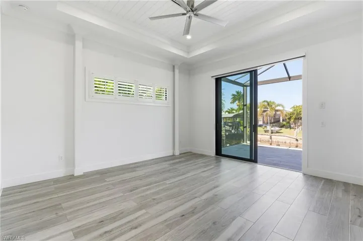 Spare room featuring a sunroom, light wood-type flooring, ceiling fan, a raised ceiling, and recessed lighting