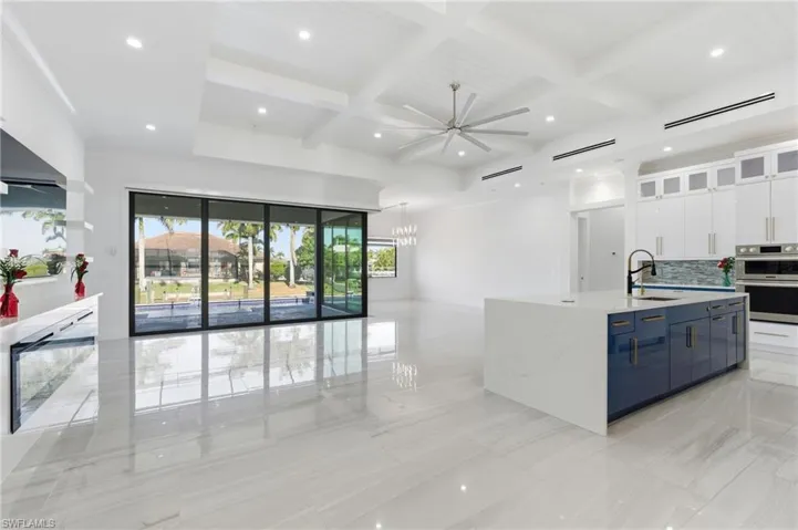 Kitchen featuring glass insert cabinets, coffered ceiling, white cabinets, tasteful backsplash, and light stone countertops