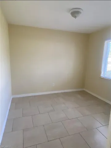 Spare room featuring light tile patterned flooring and baseboards