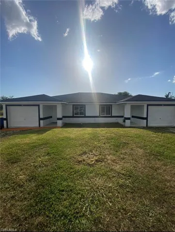 Ranch-style house featuring an attached garage and a front lawn