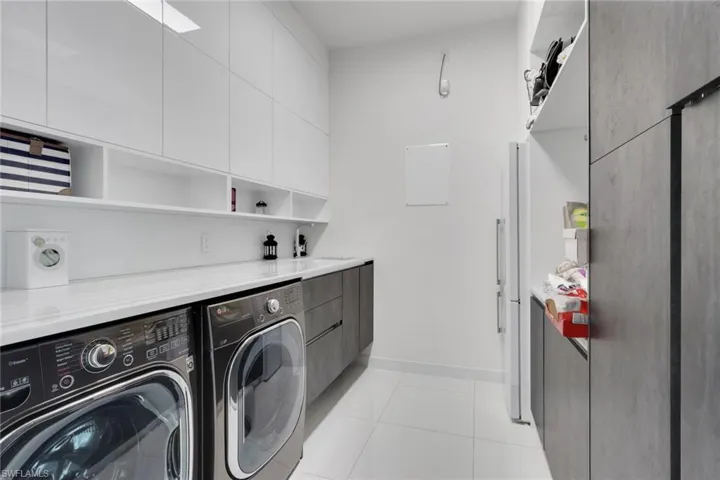Beautifully updated laundry room with marble countertops, folding area, ample storage space, extra fridge!