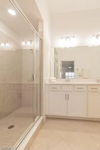 Full bathroom featuring tile patterned floors, double vanity, and a shower stall