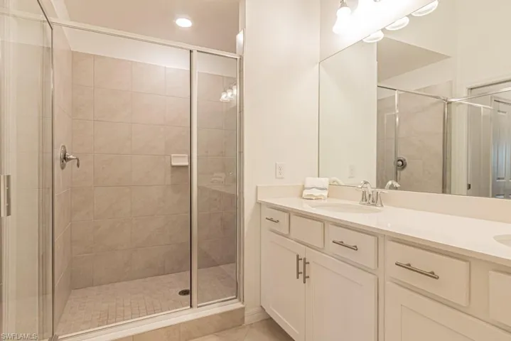 Bathroom with a stall shower, double vanity, tile patterned floors, and recessed lighting