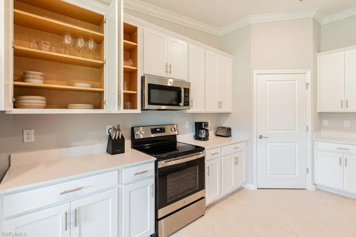 Kitchen with appliances with stainless steel finishes, open shelves, crown molding, white cabinets, and light countertops