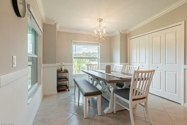 Dining space with a chandelier, ornamental molding, and light tile patterned floors