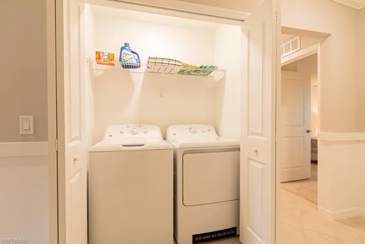 Laundry area with separate washer and dryer and light tile patterned floors