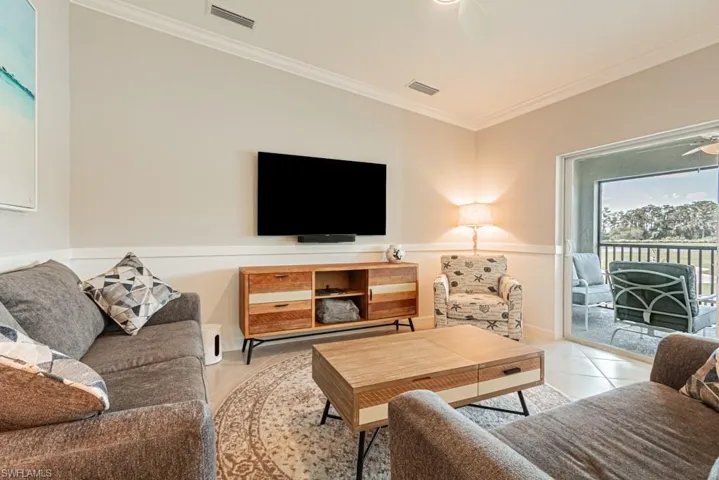 Living area with ceiling fan, ornamental molding, and light tile patterned floors