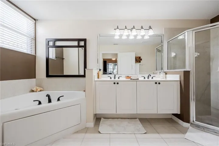 Master Bathroom featuring dual vanity, independent shower and bath, and tile flooring