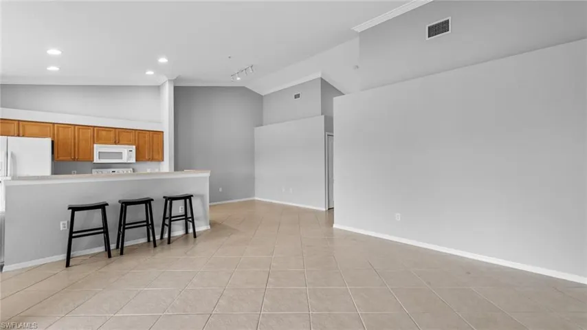 Kitchen with vaulted ceiling, brown cabinets, a kitchen breakfast bar, recessed lighting, and crown molding