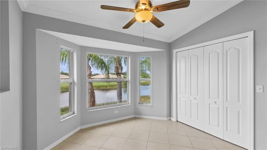 Unfurnished bedroom with ornamental molding, multiple windows, light tile patterned floors, a ceiling fan, and a closet