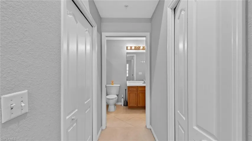 Hall with light tile patterned floors and a textured wall