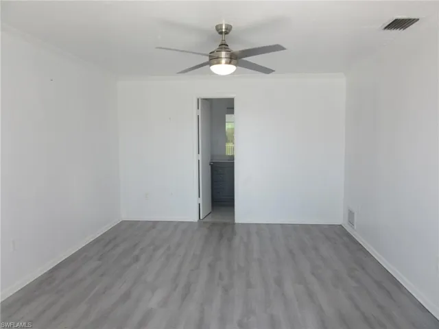 Empty room featuring ceiling fan, visible vents, crown molding, and wood finished floors