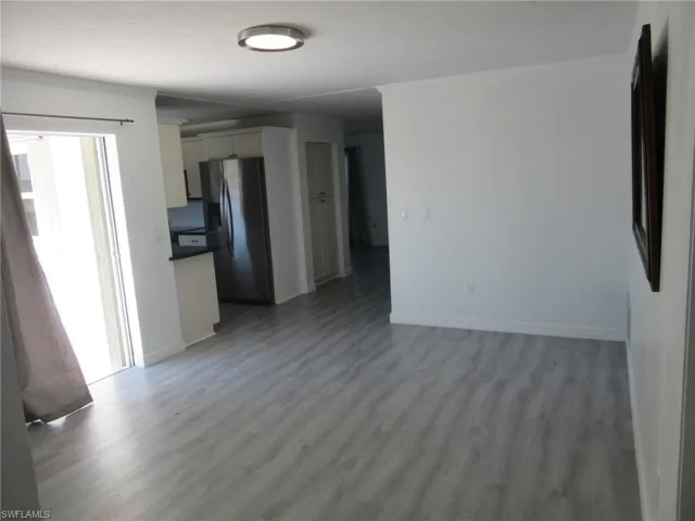 Unfurnished living room featuring baseboards, crown molding, and light wood-style flooring