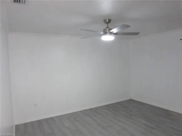 Spare room featuring baseboards, ornamental molding, wood finished floors, and a ceiling fan