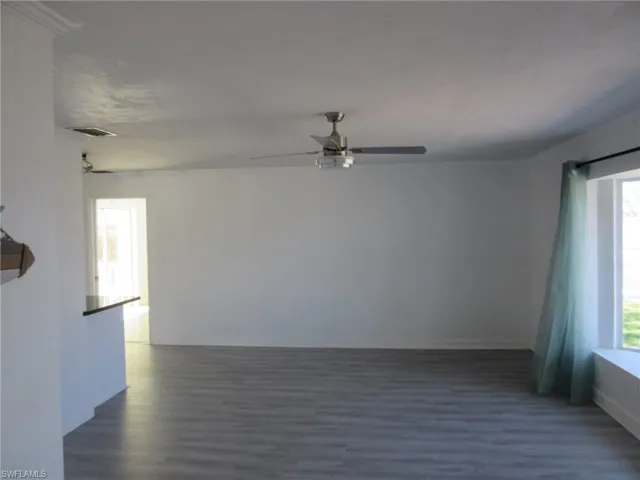 Spare room featuring baseboards, ceiling fan, visible vents, and dark wood finished floors