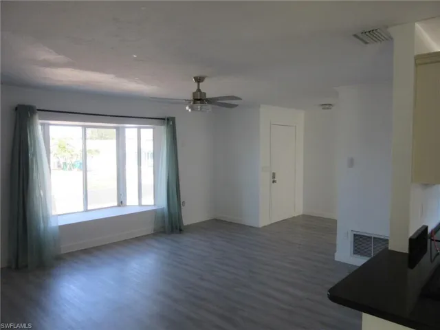 Unfurnished living room featuring baseboards, visible vents, a ceiling fan, and wood finished floors