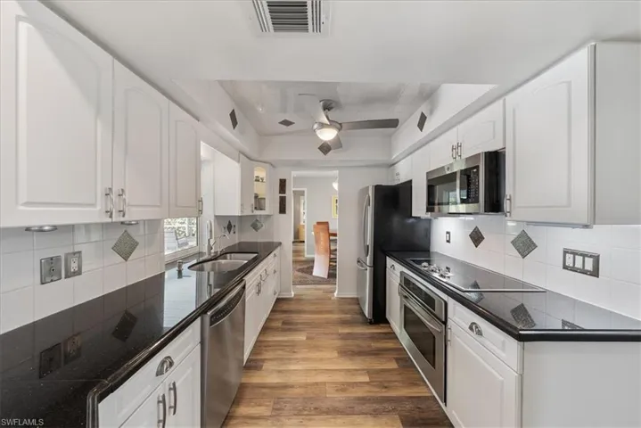 Kitchen featuring decorative backsplash, white cabinets, appliances with stainless steel finishes,