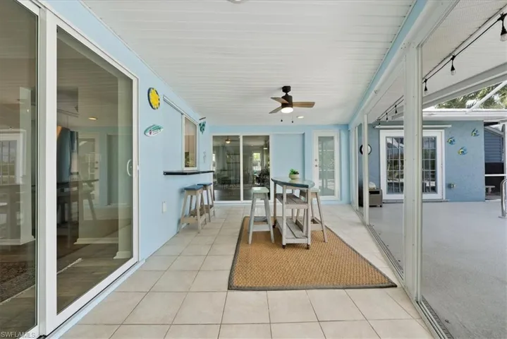 Sunroom / solarium with a ceiling fan, healthy amount of natural light, and tile patterned flooring