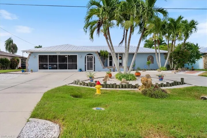 Ranch-style home with driveway, a front yard, stucco siding, and a metal roof