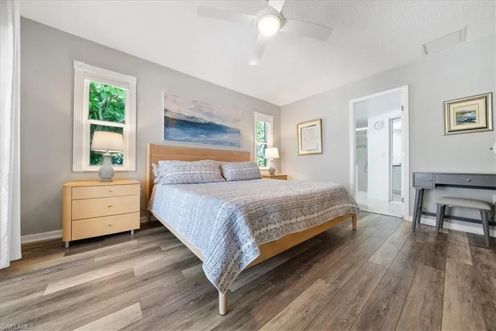 Bedroom with a textured ceiling, wood finished floors, a ceiling fan, and ensuite bath