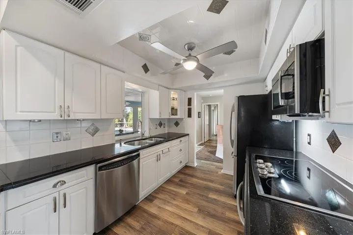 Kitchen with backsplash, white cabinets, and appliances with stainless steel finishes