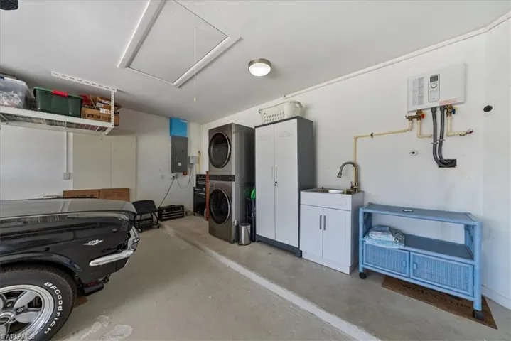 Garage featuring stacked washer / dryer, water heater, and electric panel, screen