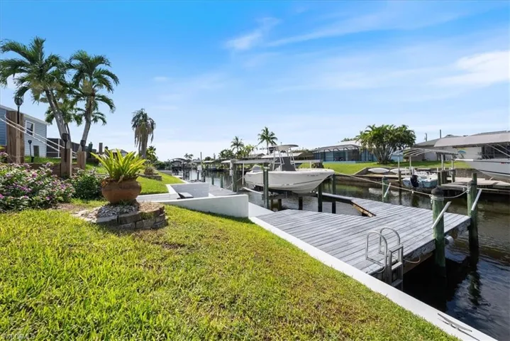 Dock area featuring boat lift, a water view, and a lawn