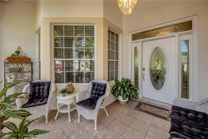 Covered front entry featuring tiled flooring, a decorative glass front door, transom window, and sidelight windows