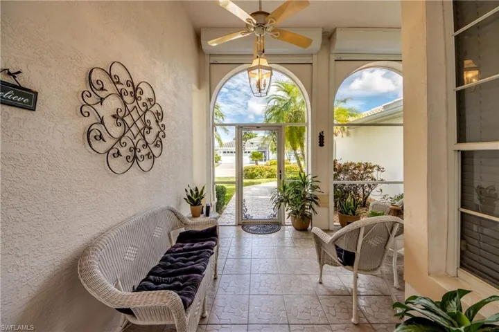 Arched entryways with screened enclosures, textured stucco wall finish, tiled flooring, and a ceiling fan with integrated lighting