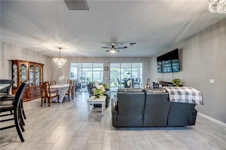 Spacious open-concept interior featuring light gray tile flooring, a contemporary chandelier, recessed lighting, and a ceiling fan
