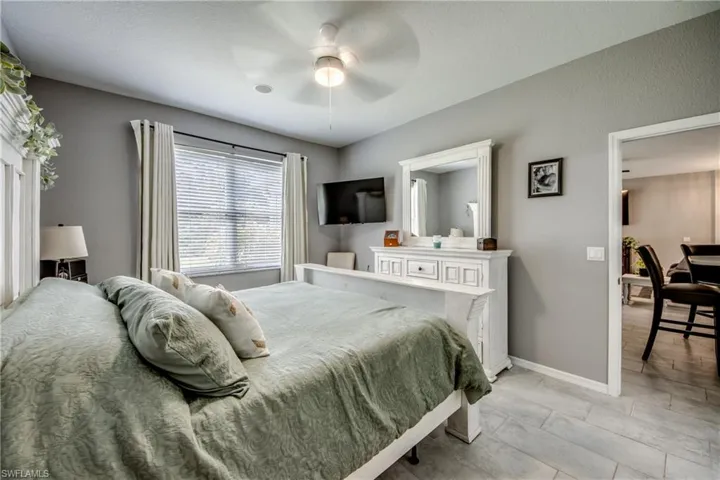 Window with blinds, ceiling fan, hard-surface flooring, and neutral wall tones