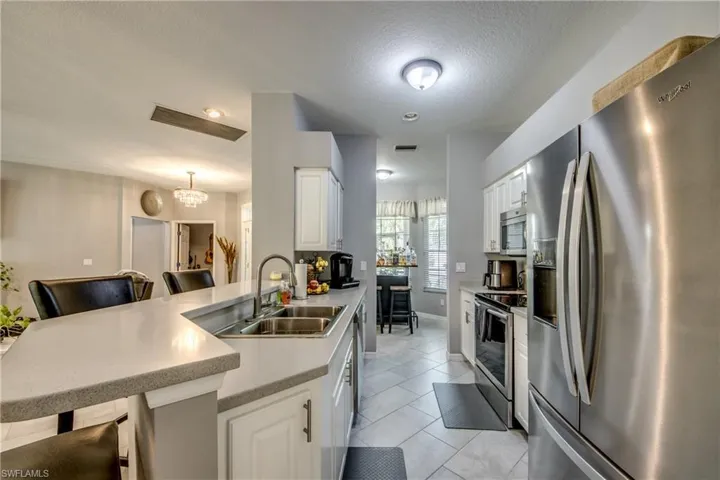 Kitchen featuring white cabinetry, stone-finish countertops, stainless steel appliances, and tile flooring
