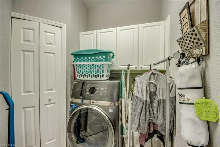 Laundry area featuring white bi-fold doors and white upper cabinetry